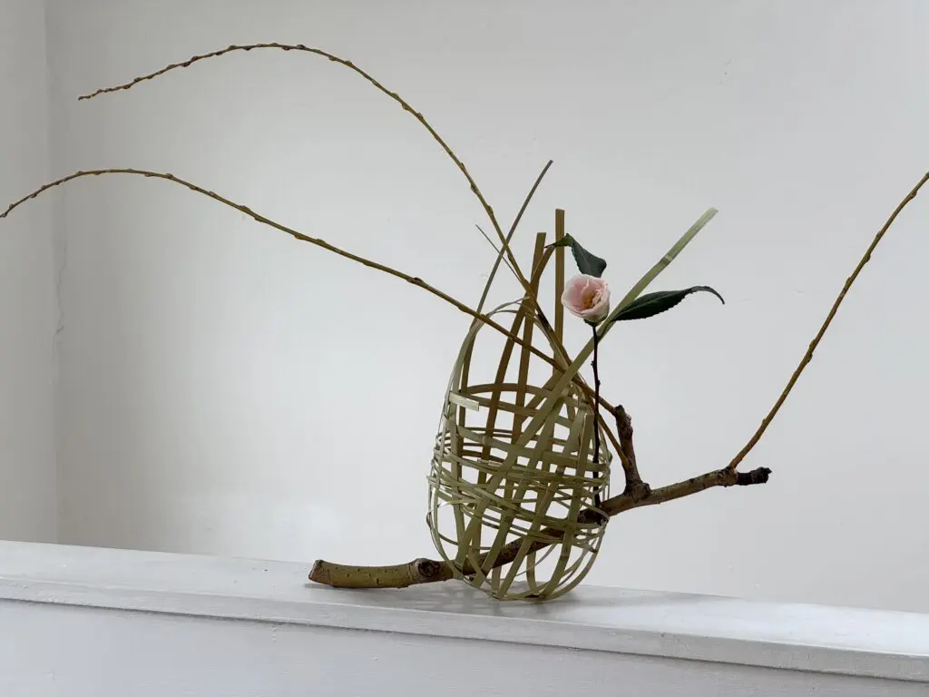 A bamboo and willow basket, with a single camellia flower